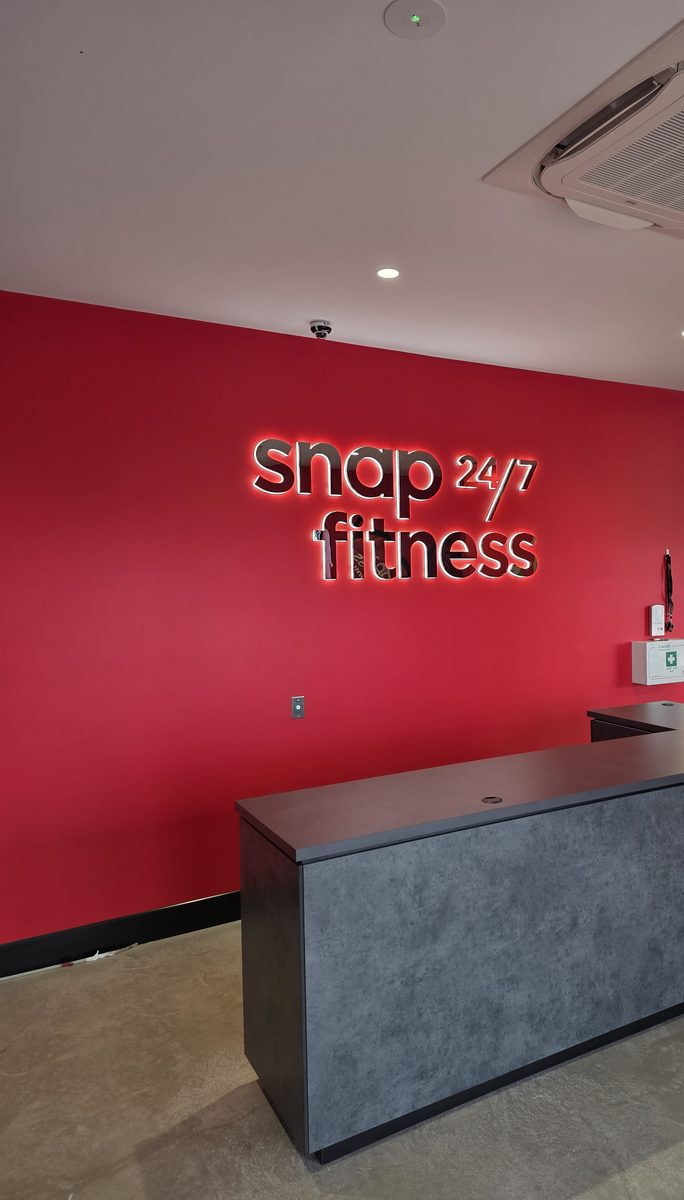 Snap Fitness Huntlee reception with illuminated Snap 24/7 Fitness signage