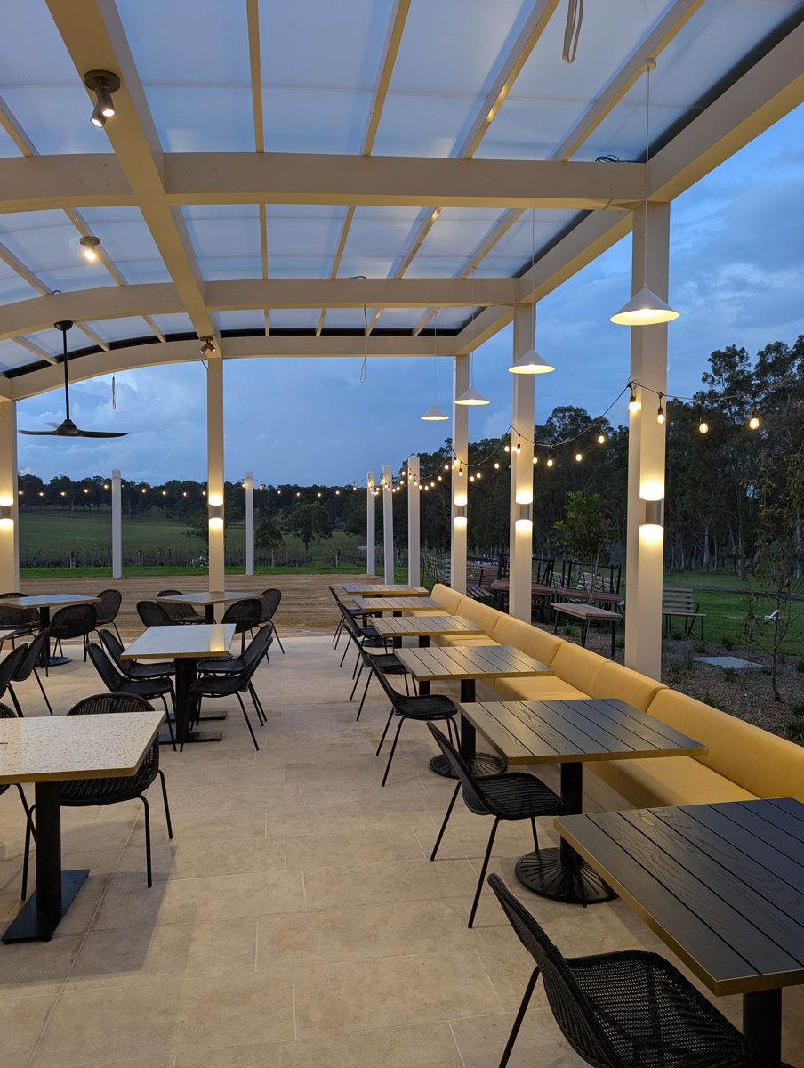 After: pergola dining at dusk, set for service