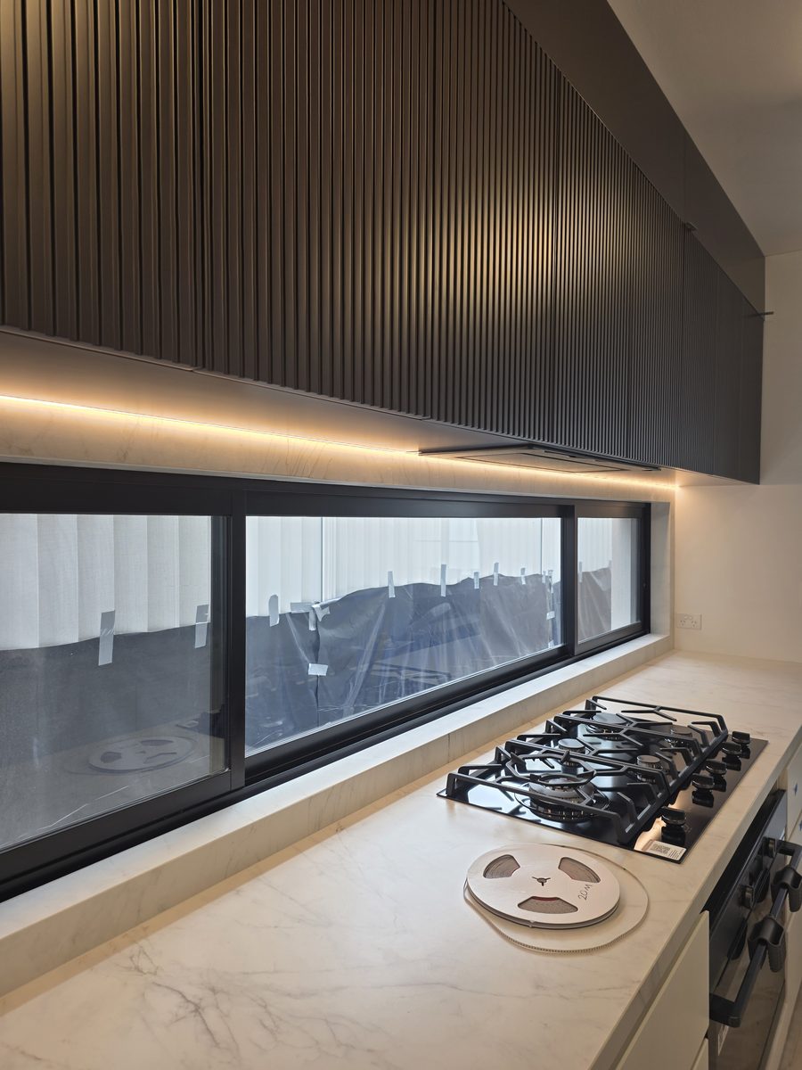 Kitchen with warm under-cabinet LED over a marble bench and cooktop, Picnic Point duplex